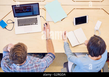 Obenliegende Bild des männlichen und weiblichen arbeiten am eigenen Schreibtisch Stockfoto