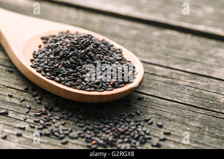 Schwarzer Sesam. Gesunden Sesam in Löffel auf Holztisch. Stockfoto