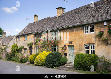 Cotswold Steinhütte Fenster mit rosa Rosen umgeben. Stanton, Cotswolds, Gloucestershire, England Stockfoto