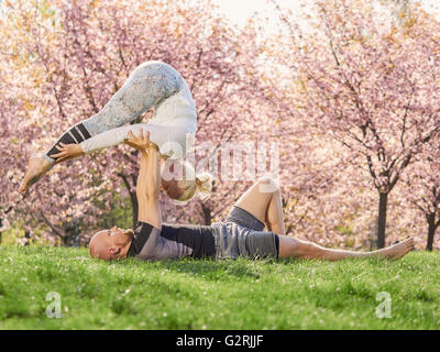 Paar training Acro Yoga in einem Park, kann Kirschblüten auf Hintergrund, im südlich von Finnland. Stockfoto