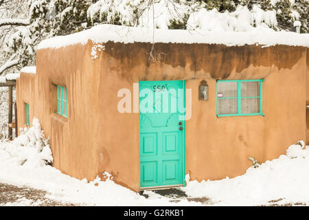Ein helles Türkis Tür auf eine Adobe-Stil Zuhause im Stadtteil Arroyo Tierra Blanca nach einem Winter Schneefall 13. Dezember 2015 in Santa Fe, New Mexico. Stockfoto