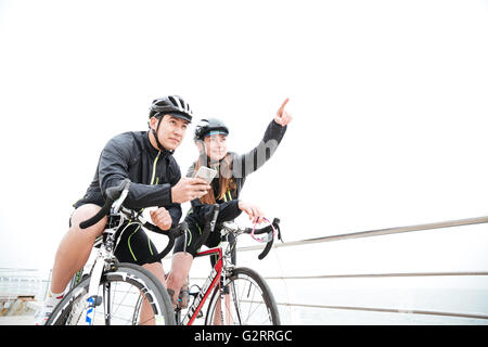 Nachdenklich junges Paar Wahl Richtung mit Smartphone und zusammen Fahrrad fahren Stockfoto