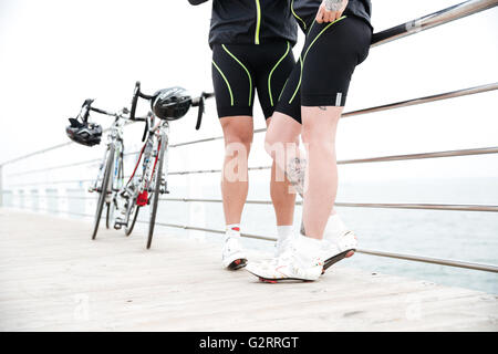 Nahaufnahme des Paares in Hosen und weiße Turnschuhe mit Fahrrädern stehen am pier Stockfoto