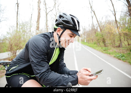 Fröhlichen jungen Mann in Schutzhelm mit dem Fahrrad mit Handy Stockfoto