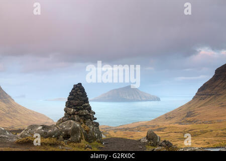 Insel Koltur Vista mit Cairn im Vordergrund von Bergen bei Sonnenaufgang auf Streymoy, Färöer, Dänemark im April - Färöer Stockfoto