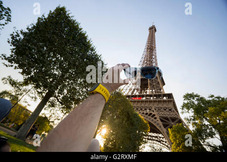 Der Eiffel-Turm von unten gesehen und eine Hand, die Sonnenschirme, so dass es scheint, als ob der Turm sie in Paris, Frankreich hatte. Stockfoto