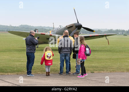 Eine Familie mit Kindern, die ein Spitfire-Flugzeug aus dem Jahr WW2 auf der Duxford Air Show, Imperial war Museum, Duxford IWM, Cambridgeshire UK, ansieht Stockfoto