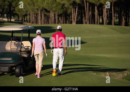 junges Paar zu Fuß zum nächsten Loch am Golfplatz. Mann Golf Tragetasche Stockfoto