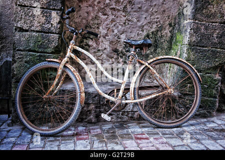 Altes Fahrrad gegen verfallene Mauer am Hafen von Essaouira, Marokko. Stockfoto