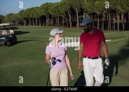 junges Paar zu Fuß zum nächsten Loch am Golfplatz. Mann Golf Tragetasche Stockfoto