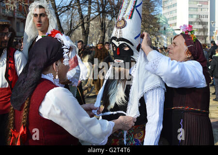 Einheimische Frauen mit traditionellen Trachten und Masken der Kukeri am Surva Festival in Pernik, Bulgarien Stockfoto