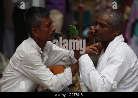 Pune, Indien - 11 Juli 2015:A Streetside Barbier rasiert Pilger während einer großen Pilgerfahrt in Indien Stockfoto