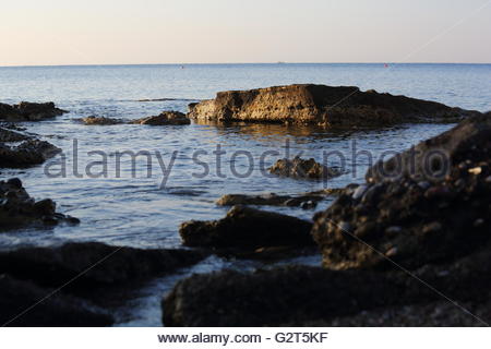 Tagesanbruch über Felsen in einer Bucht auf der Insel Rhodos in Griechenland Stockfoto