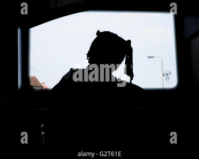 Ein junges Mädchen mit geflochtenen Haaren blickt aus dem hinteren Fenster eines Busses in London Stockfoto