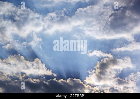 Sonnenstrahlen, die durch Wolken am blauen Himmel Stockfoto