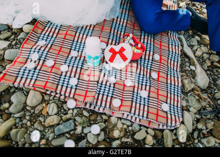 Romantisches Picknick an einem Flussufer: Tartan Tuch, Kerzen und Box mit Süßigkeiten Stockfoto