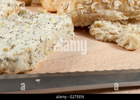 Nahaufnahme Bild von einem frisch geschnittenen entkernten Vollkorn Brötchen auf ein Steckbrett mit einem Messer Stockfoto