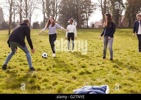 Gruppe von Jugendlichen spielen Fußball im Park zusammen Stockfoto