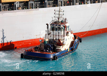 Schlepper drängen Frachter im Hafen Stockfoto