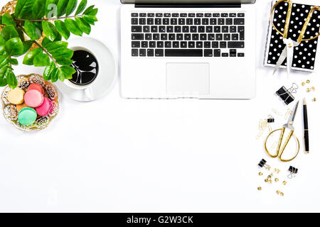 Feminine Arbeitsplatz. Kaffee, Kekse Makronen, Bürobedarf, Laptop-Computer und Grünpflanze auf weißen Tisch Hintergrund. Top vi Stockfoto