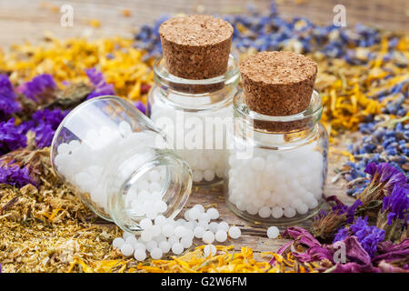 Flaschen mit Homöopathie Globuli und trockenen gesunden Kräutern auf Tisch. Selektiven Fokus. Stockfoto