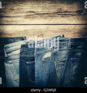 Verschiedene Jeans auf hölzernen Hintergrund im Store. Retro abgeschwächt. Stockfoto