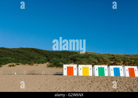 eine Reihe von weißen Strandhütten mit bunten Türen auf Woolacombe Strand, Devon an einem sonnigen Tag Stockfoto