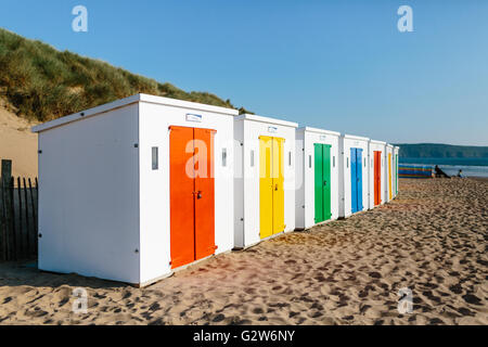 eine Reihe von weißen Strandhütten mit bunten Türen auf Woolacombe Strand, Devon. Stockfoto