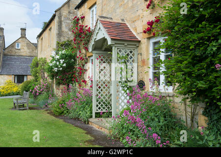 Cotswold Steinhütten mit roten Rosen. Stanton, Cotswolds, Gloucestershire, England Stockfoto