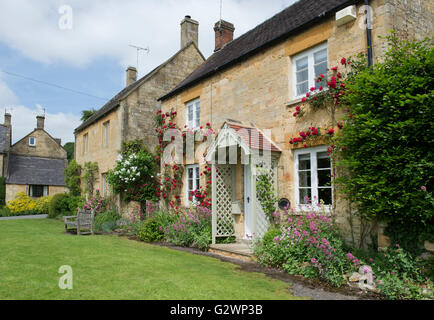 Cotswold Steinhütten mit roten Rosen. Stanton, Cotswolds, Gloucestershire, England Stockfoto