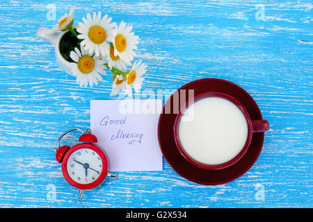 Blumen-Gänseblümchen und eine Tasse Milch mit beachten Sie guten Morgen auf rustikalen hölzernen Hintergrund Stockfoto