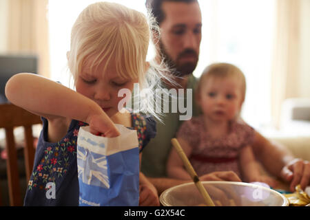 Vater mit Töchtern Backen zu Hause Kuchen zusammen Stockfoto