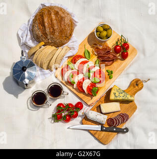 Luftaufnahme des ein Picknick im Freien, bestehend aus Bauernbrot, Ciabatta, Espresso Tassen, Oliven, Tomaten, Parmaschinken, mozzarella Stockfoto