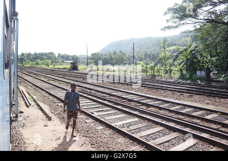 Ein junger Mann geht auf die Bahngleise in einer Kleinstadt in der Nähe von Kandy, Sri Lanka. Stockfoto
