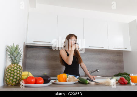 Porträt einer schönen jungen lächelnde Frau. Junge Mädchen das Kochen in der neuen Küche. Vorbereitung von Salat. Stockfoto