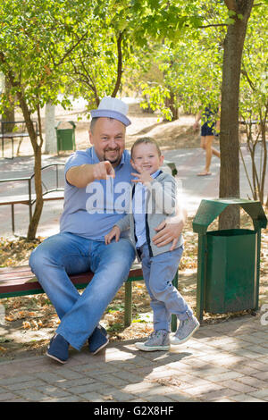 der Vater mit dem Sohn im Park auf einer Bank sitzen und Spaß haben Stockfoto