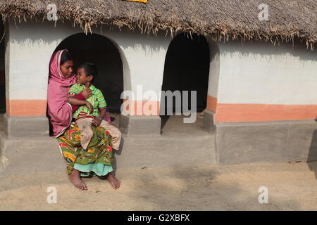 eine Stammes-Dame mit ihrem Sohn in ihrem schönen Lehmhütte in Raiganj, Westbengalen Stockfoto