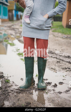 Frauen in Gummistiefel stehen in einer Pfütze Stockfoto