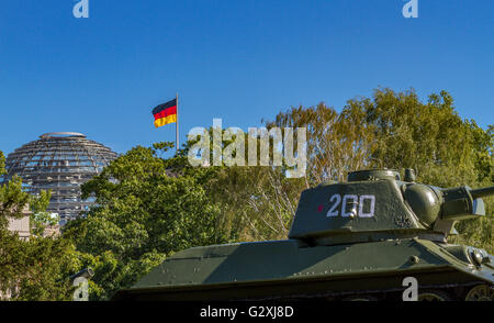 Ein russischer Panzer T-34 am sowjetischen Kriegsdenkmal im Tiergarten, mit der Glaskuppel des Reichstagsgebäudes, sichtbar durch die Bäume, Berlin Stockfoto