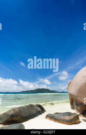 Granitfelsen am Anse Grosse Roche in La Digue, Seychellen mit klarem Wasser und blauer Himmel Stockfoto