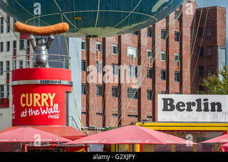 Ein Bär mit einer frankfurter auf einer hohen, in Berlin in der Nähe der Berliner Mauer verkaufenden Currywurst Stockfoto