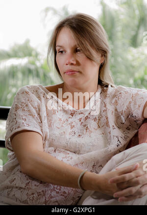 Nachdenkliche schwangere Frau sitzen auf der Terrasse-Fenster Stockfoto