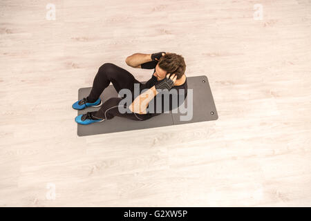 Vogelperspektive eines jungen Mannes Sit auf dem Boden in einem Fitnessstudio. Stockfoto