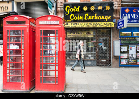 Ein Mann geht der Gold Münze Austausch zu Charring Cross Road neben zwei leuchtend rote K6 Londoner Telefonzellen Stockfoto