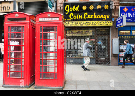 Ein Mann geht der Gold Münze Austausch zu Charring Cross Road neben zwei leuchtend rote K6 Londoner Telefonzellen Stockfoto