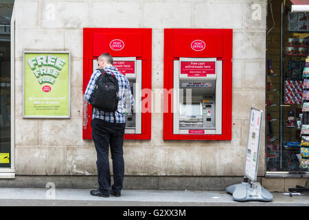 Ein einziger weißer Mann, der Bargeld von einem Geldautomaten in der Duncannon Street in der Nähe des Trafalgar Square in London, England, Großbritannien abzieht. Stockfoto