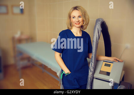 junge Frau Doktor an der Maschine Vakuum Roller Massage vor dem Eingriff Stockfoto