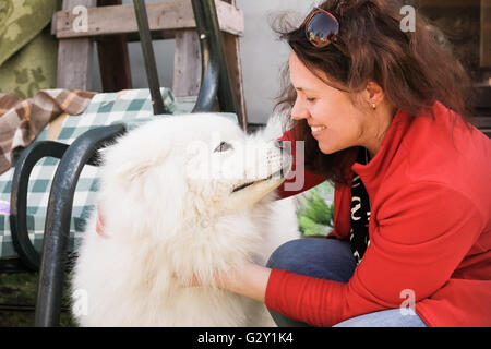 Glückliche junge Frau mit weißen flauschigen Samoyed Hund Stockfoto