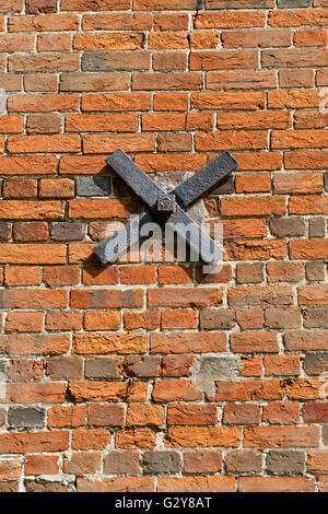 Ziegelwand mit Eisen X auf Stadtstraße in England Stockfoto