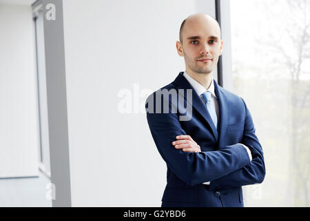 Porträt des ruhigen jungen Geschäftsmann am Fenster stehend. Hellen Hintergrund. Stockfoto